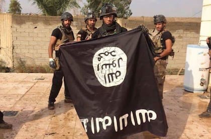 Militares iraquíes con una bandera de Estado Islámico