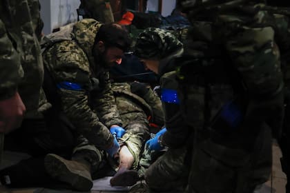 Militares ucranianos prestan primeros auxilios a un soldado herido en un refugio de Soledar, escenario de intensos combates con las fuerzas rusas en la región de Donetsk, Ucrania, el domingo 8 de enero de 2023.