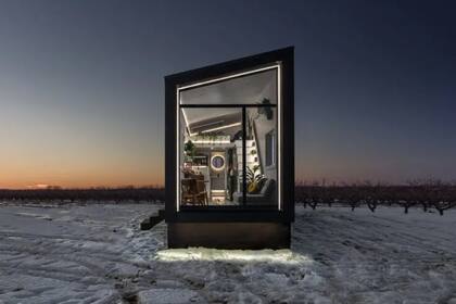 Minicasa revestida en acero de color negro sobre un terreno nevado