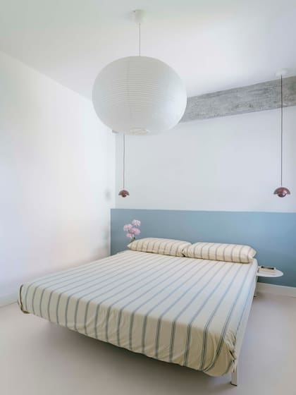Minimalista, la iluminación combina una lámpara esférica ‘Akari’ de papel, clásico diseño de Isamu Noguchi, con luminarias suspendidas a cada lado de la cama.