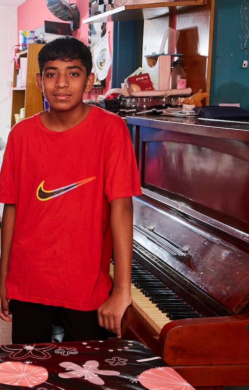 Miqueas, de 14 años, junto al piano que le regalaron y tiene en su casa
