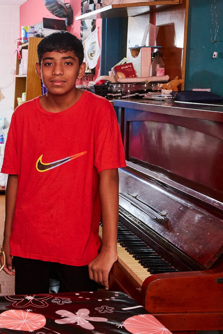 Miqueas, de 14 años, junto al piano que le regalaron y tiene en su casa