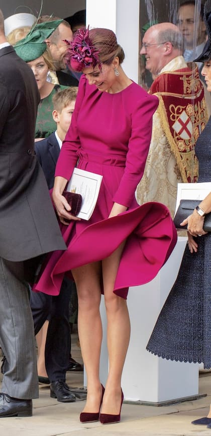 Con humor, la duquesa de Cambridge intenta dominar una vez más, su vestido frente a la ventisca de otoño.