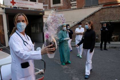 Mónica Carfora, subdirectora de emergencias del Hospital Santo Spirito, sostiene un huevo de Pascua de chocolate mientras se toma un descanso con su equipo para una pequeña celebración de Pascua fuera de la entrada a la emergencia, en el centro de Roma, domingo 12 de abril de 2020.