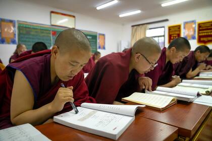 Monjes budistas tibetanos leen sus libros de texto en una clase de chino en la Escuela Budista Tibetana, cerca de Lhasa, en la región autónoma china de Tíbet, el 31 de mayo de 2021. (AP Foto/Mark Schiefelbein)