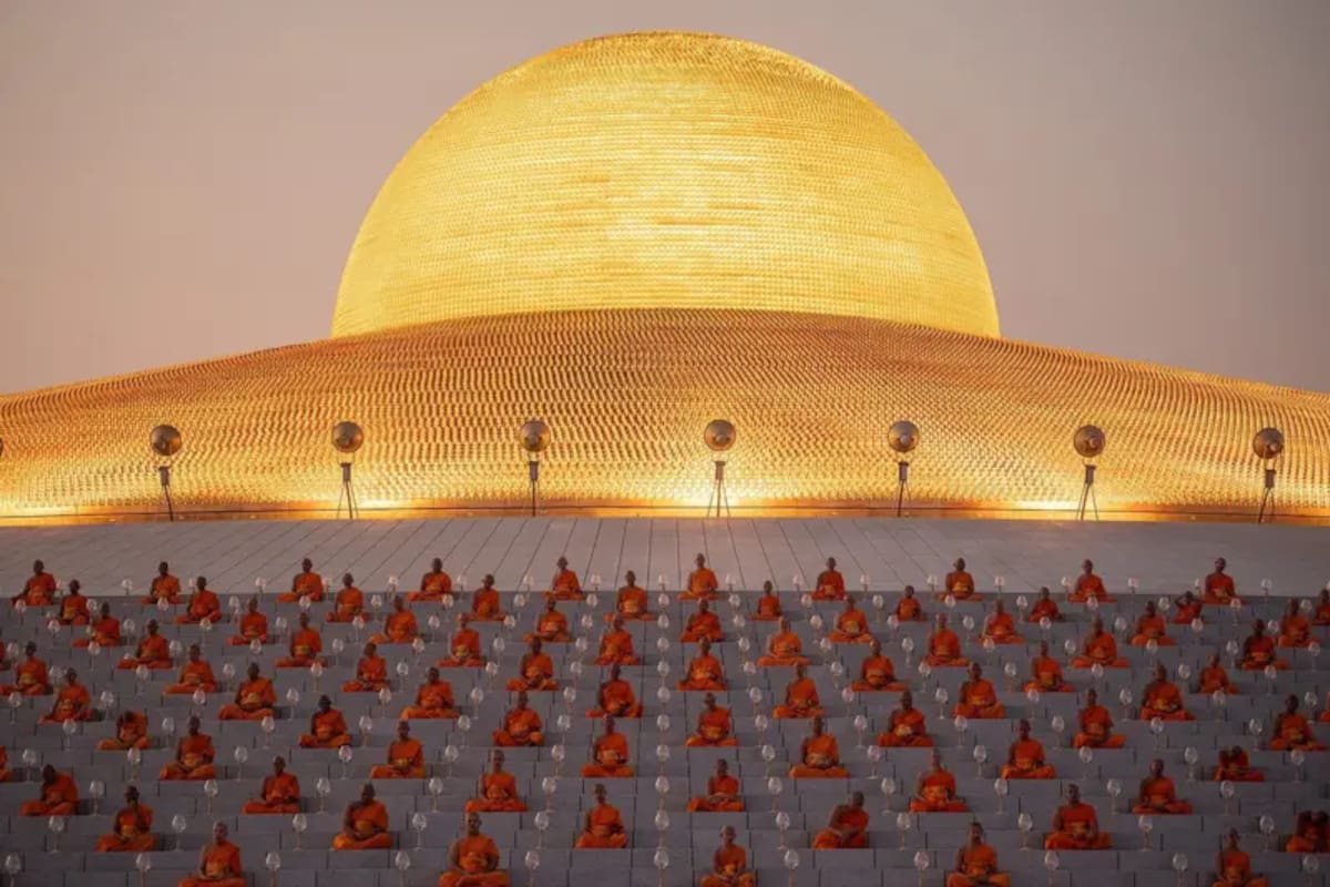 Monjes orando bajo la inmensa cúpula dorada de Wat Phra Dhammakaya