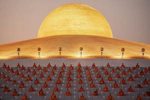 Monjes orando bajo la inmensa cúpula dorada de Wat Phra Dhammakaya