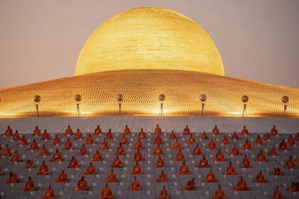 Monjes orando bajo la inmensa cúpula dorada de Wat Phra Dhammakaya