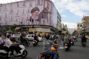 Motociclistas pasan frente a una imagen del ayatollah Ali Khamenei