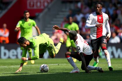 Moussa Djenepo del Southampton' derecha, derriba a Cristiano Ronaldo del Manchester United en partido de la Liga Premier inglesa en el St Mary's Stadium, Southampton, Inglaterra, sábado 27 de agosto de 2022. ManU ganó 1-0. (Kieran Cleeves/PA via AP)