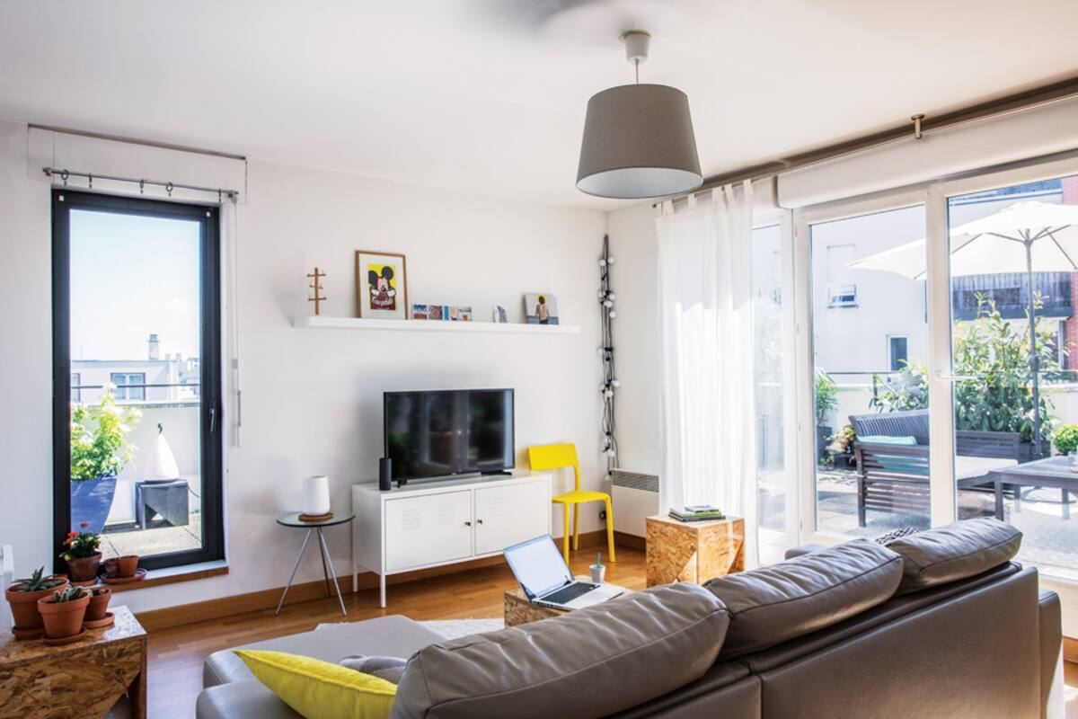 Mueble blanco y silla amarilla de Ikea. La mesa de tres patas con tapa de vidrio (Habitat) sostiene un jarrón de Hema, una gran tienda holandesa