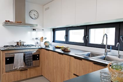 Mueble de cocina (diseño de la arq. Carolina Fernández Igartúa) de melamina texturada ‘Roble miel’ (Egger). Mesada de granito negro absoluto terminación ‘Leather’ (Artecnia) con alzada de Neolith ‘Arctic White’ (De Stefano). La alacena no comparte color con el bajomesada; blanca y sin tiradores, se funde con la pared.