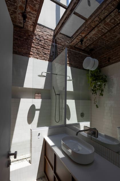 Mueble de madera enchapada en petiribí, diseñado a medida por el Estudio, con mesada de cuarzo ‘Cimstone’ (Fiesta), bacha (Deca) y grifería (Home Inox) instalada sobre el espejo.