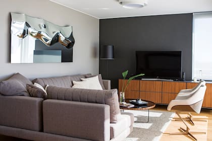 Mueble de TV, sillón 'Mercury', espejo-cuadro de diseño italiano (todo de Walmer). Lámpara 'Hi Hat' con pantalla negra (Kikely). Plafón dimerizable (Griscan). Pisos de roble de Eslavonia (Patagonia Flooring).