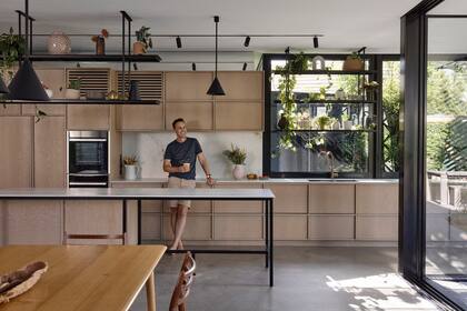 Muebles de chapa de roble americano, hierro en marcos estantes e iluminación, y mesadas blancas: la receta de una elegante sencillez.