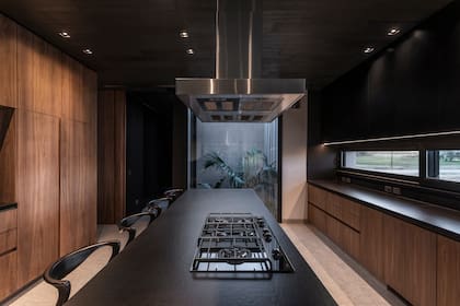 Muebles de cocina enchapados en nogal americano, con terminación en hidrolaca poliuretánica mate. Mesada e isla de Dekton Sirius de 12 mm.