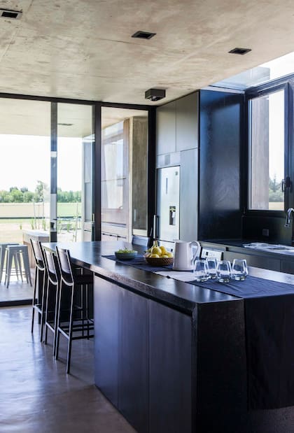 Muebles de cocina laqueados en gris (AtelierM). Mesada de granito negro con terminación leather. Apliques de iluminación negros (Housing).