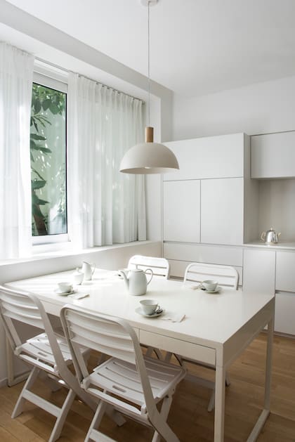Muebles de cocina (Mazzinghi-Sánchez Arquitectos) de melamina blanca con mesada de Purastone. Mesa con estructura de hierro pintada de blanco y sillas de PVC.
