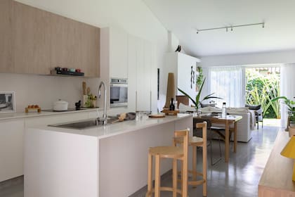 Muebles de MDF laqueado con alacenas en melamina ‘Roble Escandinavo’ de Faplac (diseño de Sara Plazibat). Mesadas de Igneastone ‘Classical White’ (Itatí Marmolería). Bacha ‘Q71’ (Johnson Acero) con grifería FV ‘Temple’ (De Todo Sanitarios). Banquetas ‘Orno’ (Ries). Los artefactos de iluminación del techo, diseño de la arquitecta, fueron ejecutados por Paraná 201.