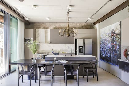 Muebles laqueados, alzada de Neolith y grifería Hansgrohe. La mesa de comedor se pensó como una extensión de la isla (Carpintería Palo Santo) y se rodeó de sillas ‘Wishbone’.