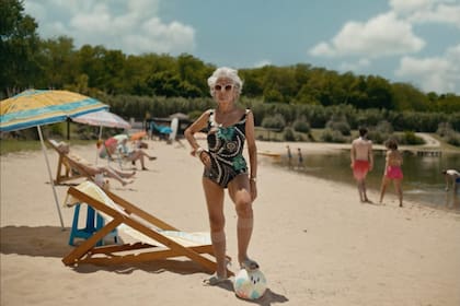 Mujer anciana en la playa con pelota.