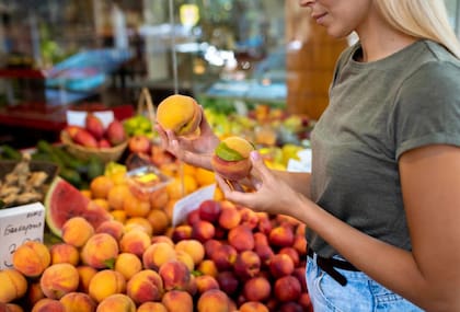 Mujer elije frutas en un mercado. Foto: Freepik.