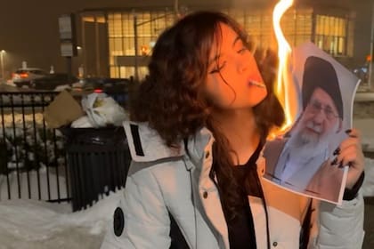 Mujer iraní enciende un cigarrillo con una foto en llamas del líder supremo Ali Khamenei (Publicado en X)