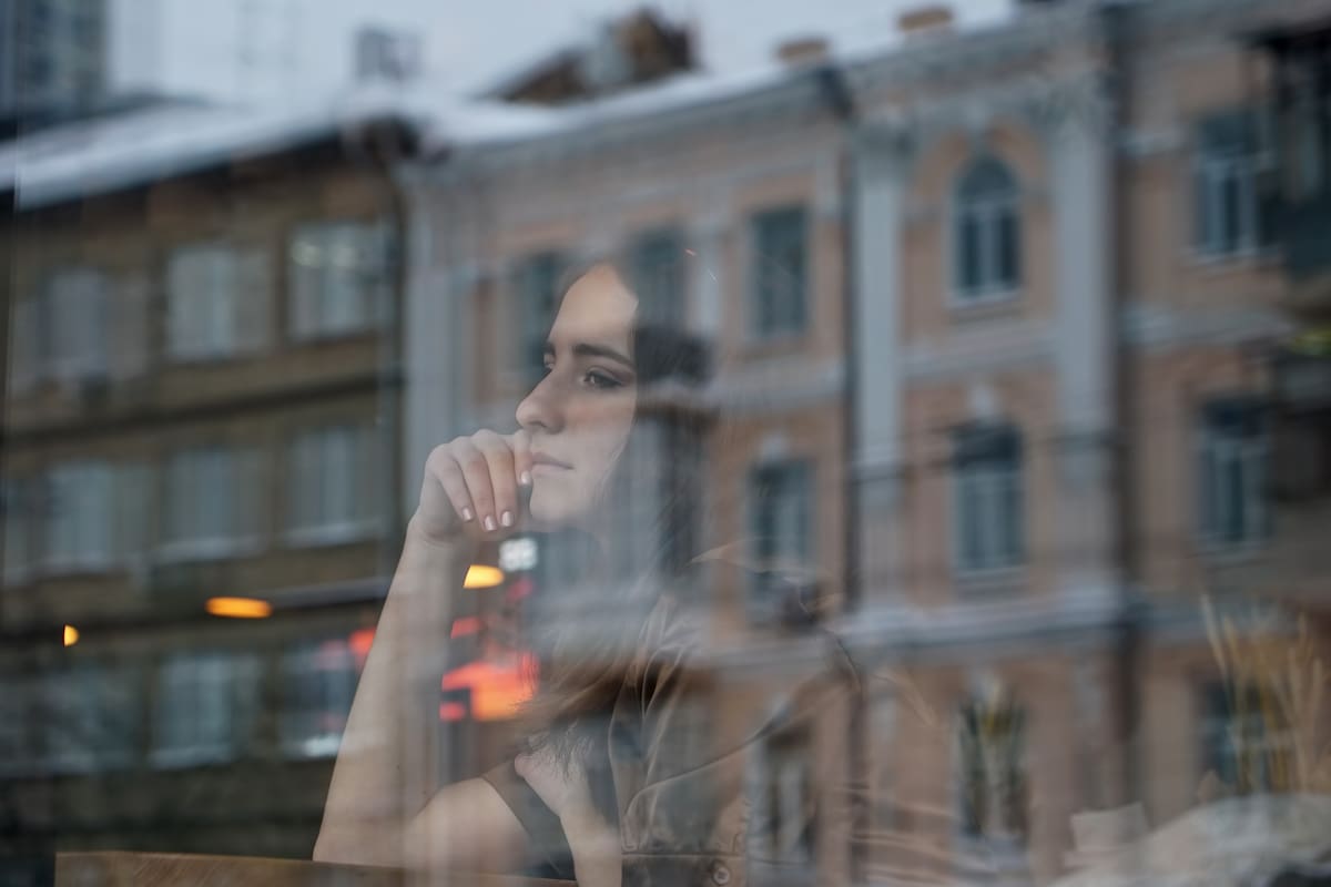 Mujer joven mira a través de una ventana.