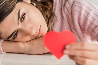 Mujer observa un corazón de papel con cara triste