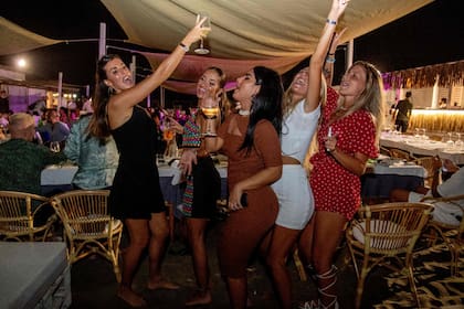 Mujeres bailan en la arena en un restaurante al aire libre de una playa en Fregene, cerca de Roma, el 14 de agosto de 2020