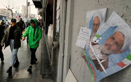 Mujeres pasan junto a carteles electorales con la imagen del ayatolá Alireza Arafi