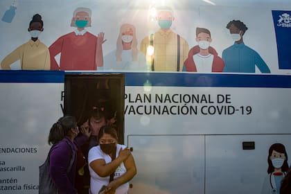 Mujeres salen de un autobús que se usa para inyectar la vacuna contra COVID-19 en Santiago, Chile