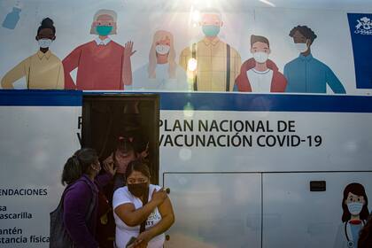 Mujeres salen de un ómnibus que se usa para inyectar la vacuna en Santiago, Chile (AP Foto/Esteban Felix)