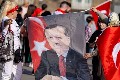 Mujeres sostienen un retrato del presidente de Turquía, Recep Tayyip Erdogan, mientras celebran en el norte de Duisburg, Alemania, domingo 28 de mayo de 2023.
