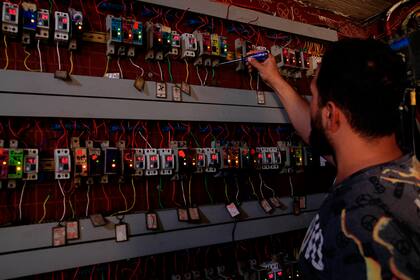 Muqtada Haider activa interruptores para transmitir electricidad a viviendas privadas en bagdad, Irak, el viernes 10 de septiembre de 2021.  En Irak, la electricidad es un potente símbolo de la corrupción endémica, arraigada en el sistema de reparto de poder del país en función de los grupos religiosos. (AP Foto/Hadi Mizban)