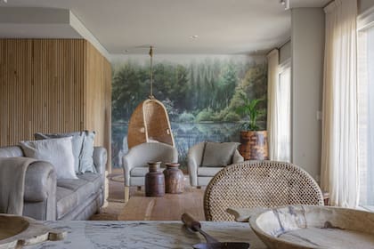 Mural de Sofía Willemoës. Sillón Chesterfield de cuero gris, sillones
en lino, alfombra de yute, mesas bajas, objetos de teca de la India y maceta con palmera de Indonesia (todo de Compañía Nativa).