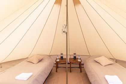 Nada de bolsas de dormir: carpas y mesas de luz. Un glamping de ley.