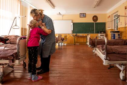Nadia besa a su nieta de 10 años, Zlata Moiseinko, quien padece una afección cardíaca crónica, mientras recibe tratamiento en una escuela convertida en hospital de campaña en Mostyska, en el oeste de Ucrania, el jueves 24 de marzo de 2022. (Foto AP/Nariman El-Mofty)
