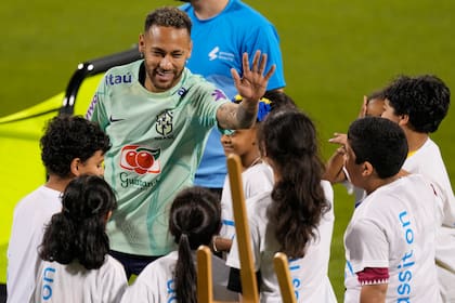 Neymar saluda a niños de un proyecto de la FIFA en un entrenamiento en el estadio Grand Hamad en Doha, en la previa del debut mundialista