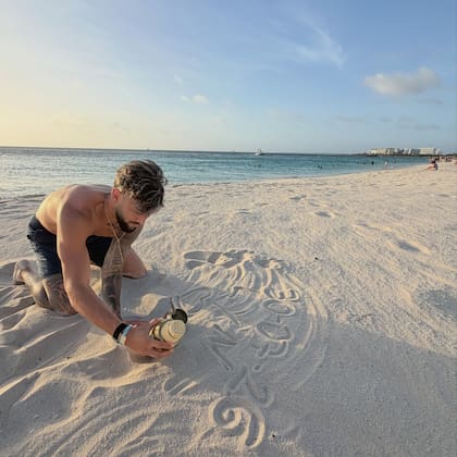 Nico fue retratado de rodillas en la orilla, personalizando el diseño en la arena antes del atardecer (Foto: Instagram/@ludisabella)