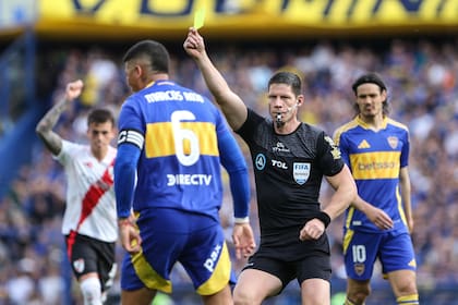 Nicolás Ramírez le muestra la amarilla a Marcos Rojo en su primer Superclásico, en 2024