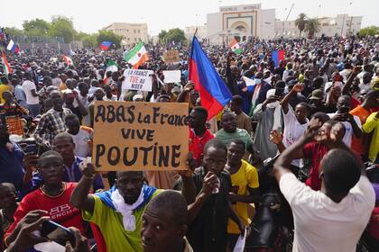 Nigerinos participan en una marcha convocada por los partidarios del líder golpista, el general Abdourahmane Tchiani, en Niamey, Níger, domingo 30 de julio de 2023. Días después de que soldados amotinados derrocaran al presidente democráticamente elegido de Níger, aumenta la incertidumbre sobre el futuro del país y algunos denuncian las razones de la junta para hacerse con el control. El cartel dice: "Abajo Francia, viva Putin". (AP Photo/Sam Mednick)