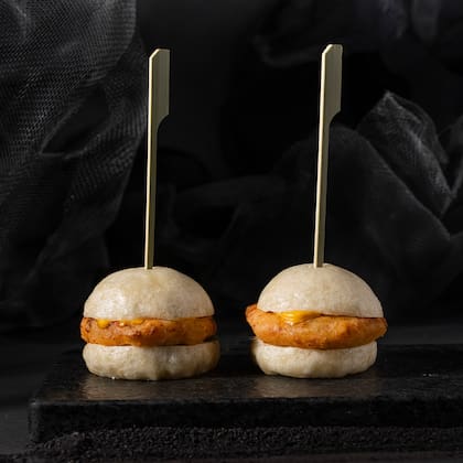 Nikkei Baos: dos mini hamburguesas de pan bao rellenas de langostinos y pollo, bañadas en salsa acevichada. Un formato de origen asiático reinterpretado con sabores peruanos.
