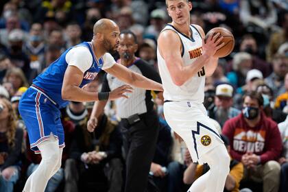 Nikola Jokic, derecha, de los Nuggets de Denver, es defendido por Taj Gibson, de los Knicks de Nueva York, durante la primera mitad del juego de la NBA, el martes 8 de febrero de 2022, en Denver. (AP Foto/David Zalubowski)