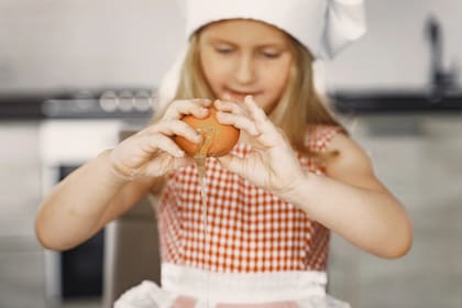 Niña cocina con huevos