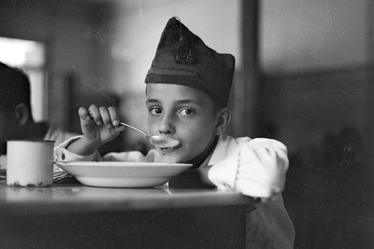 Niño levantando la vista mientras toma sopa. Madrid 1936-37.