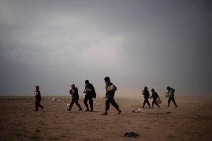 Niños evacuados del último territorio que mantienen los militantes del Estado Islámico caminan en un centro de detección después de recolectar alimentos, en las afueras de Baghouz, Siria, el 26 de febrero. Las evacuaciones han continuado en medio de un enfrentamiento entre los militantes y el partid