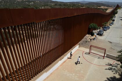 Niños juegan al fútbol en una cancha junto al muro fronterizo entre México y Estados Unidos, en Tecate, estado de Baja California, México