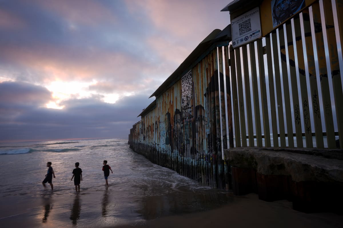Niños juegan cerca de donde el muro fronterizo entre Estados Unidos y México llega al océano Pacífico, el 21 de febrero del 2025, en Tijuana, México