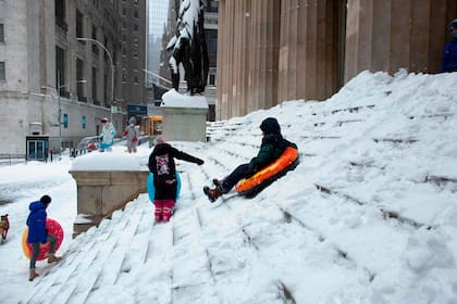 Niños juegan en unas escaleras congeladas en Wall Street
